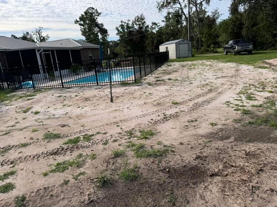 Backyard with a fenced pool, tire tracks on sandy ground, and a nearby shed and truck.