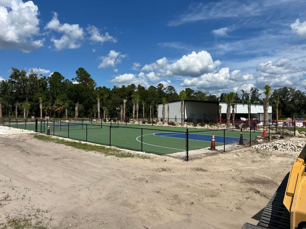 Newly built sports court surrounded by palm trees and under a blue sky with clouds.